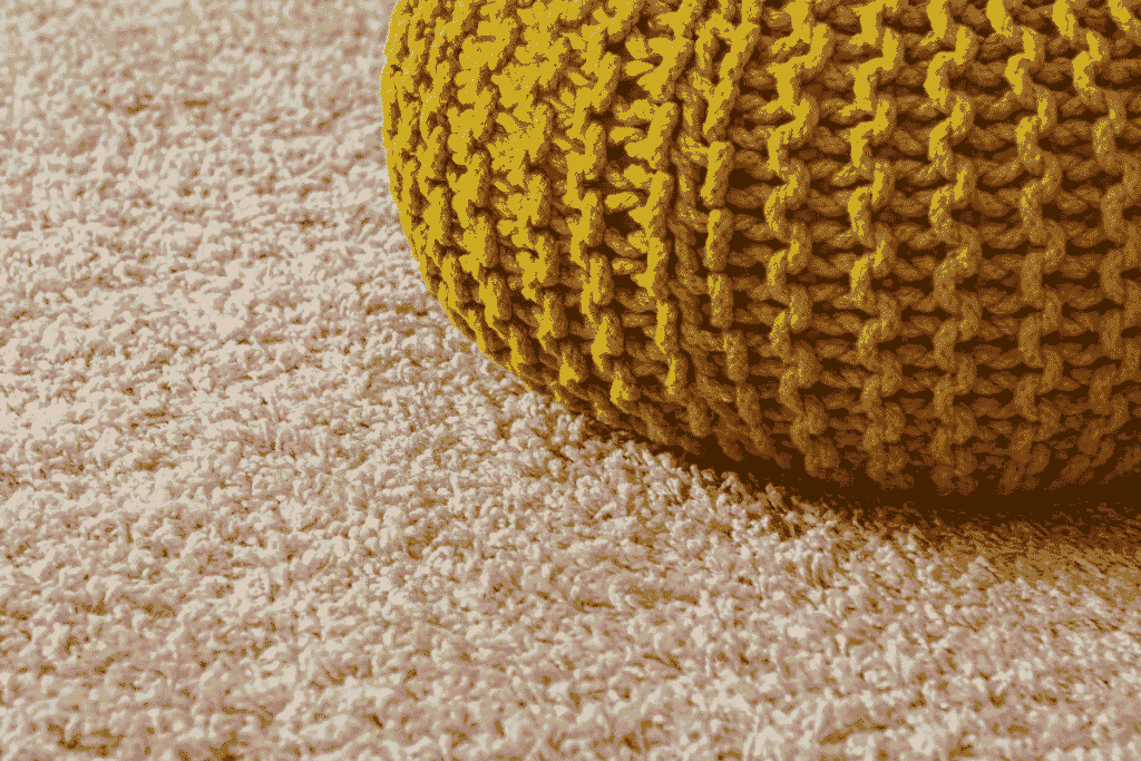 Beige carpet with soft textured fibers and a yellow knitted pouf placed on top.
