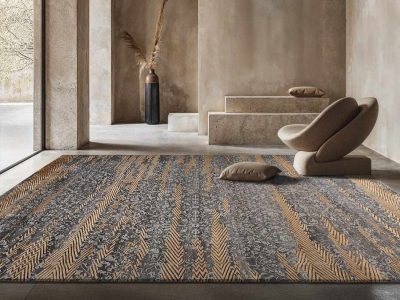 Modern living room with a large patterned carpet in grey and gold tones, paired with a minimalist lounge chair and neutral decor.